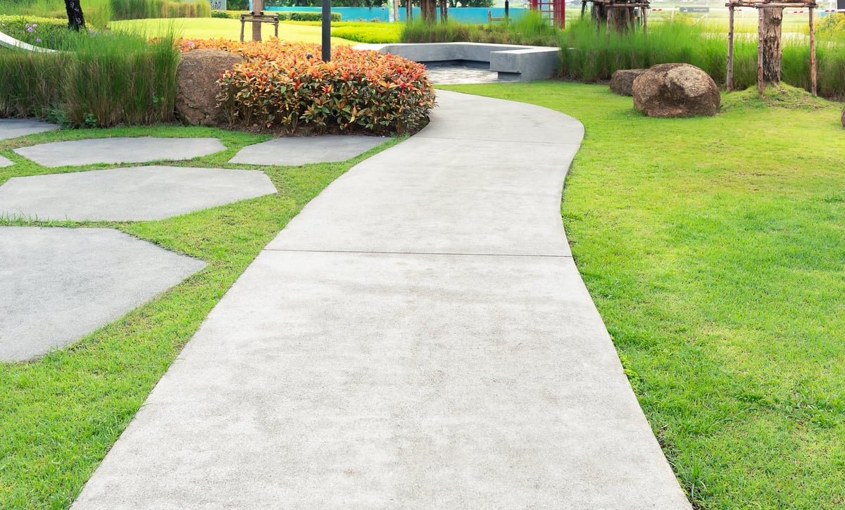 Clean concrete walkway leading to front entry with landscaping