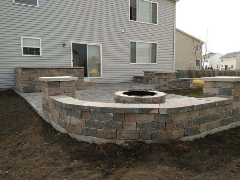Backyard patio with curved stone retaining wall and central fire pit